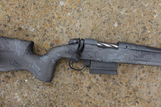 Bergara B14 Crest Carbon rifle, showcasing a carbon fiber stock, heavy profile barrel, and muzzle break, lying on a surface.