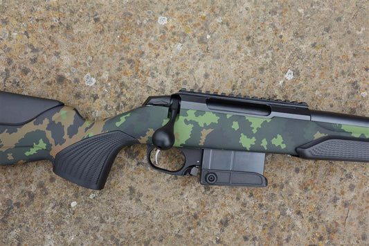 Tikka T3X CTR Camo rifle with a scandi camo stock, heavy barrel, detachable magazine, and picatinny rail, displayed on the ground.