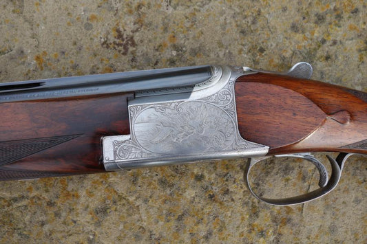 Close-up of a Browning B25 C2G Skeet gun, featuring engraved birds on the metal and a well-figured stock with a wide skeet forend.