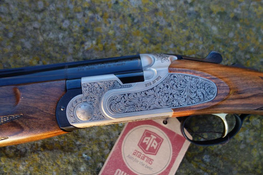 ATA Silverline Sideplate Game close-up featuring intricate folate scroll engravings, black barrels, and Turkish walnut stock with visible trigger mechanism.