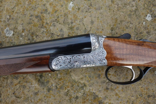 Rizzini BR550 Side by Side featuring elegant scroll engraving, walnut stock with pistol grip, visible trigger, and gun barrel details.