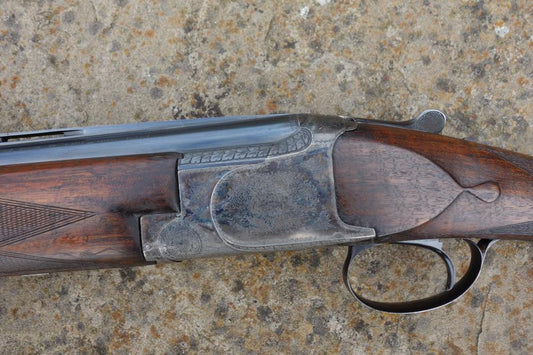 Close-up of the Browning B25 C1 Trap gun, showcasing its engraved receiver, rounded pistol grip, and narrow top rib, highlighting original features and craftsmanship.