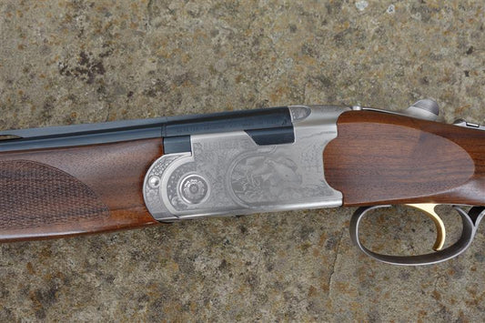 Close-up of a Beretta 687 Silver Pigeon 3 Game firearm, showing the trigger and barrel, with intricate game scenes and Turkish walnut stock detailing.