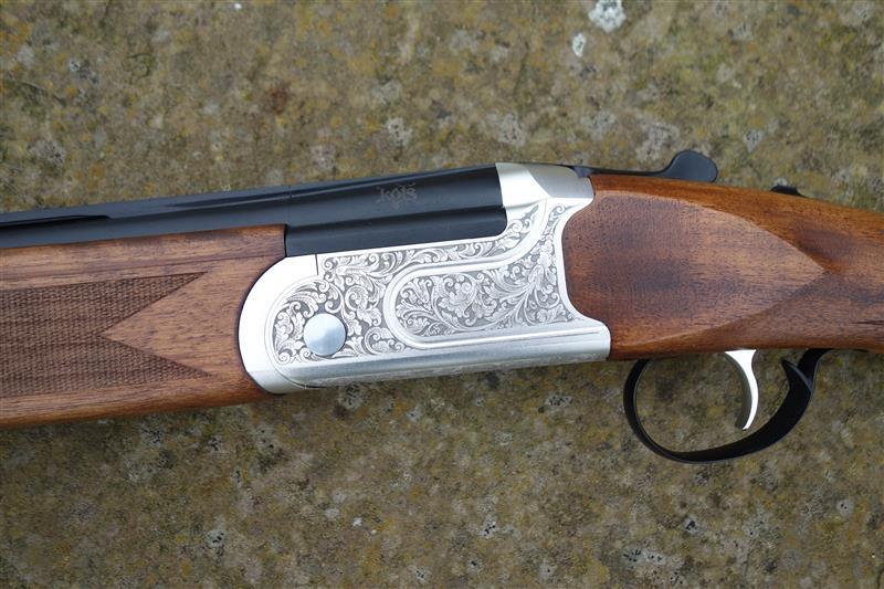 Close-up of the Kofs Sceptre SXE Game, showcasing the firearm's trigger, gun barrel, and finely figured stock, featuring HP steel proofing and auto safety catch.