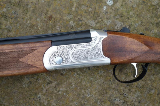 Close-up of the Kofs Sceptre SXE Game, showcasing the firearm's trigger, gun barrel, and finely figured stock, featuring HP steel proofing and auto safety catch.
