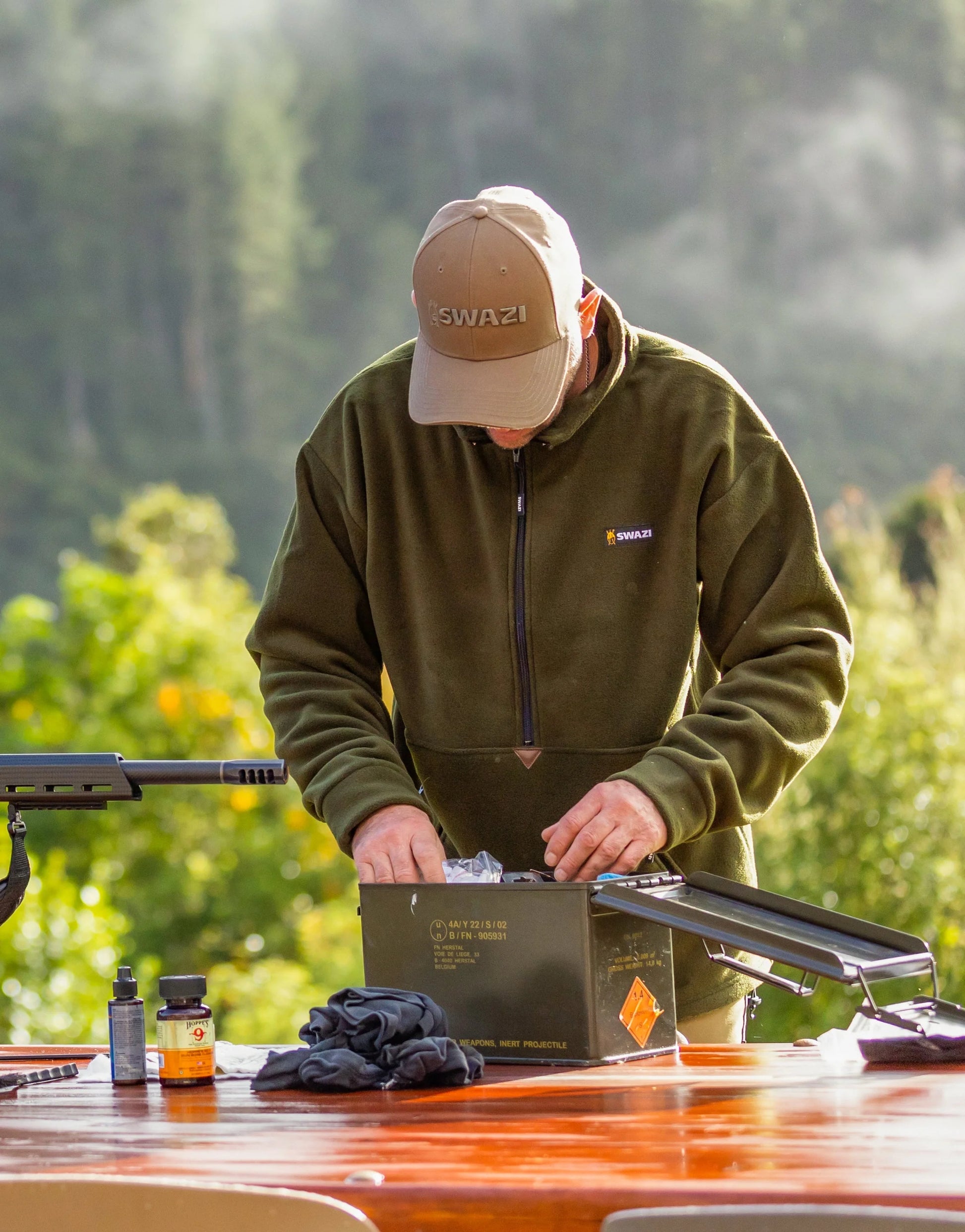 Man wearing Swazi Doughroaster Fleece Jumper, adjusting box. Features a long zip, high collar, large pocket, and adjustable hem. Ideal for comfort and versatile use.