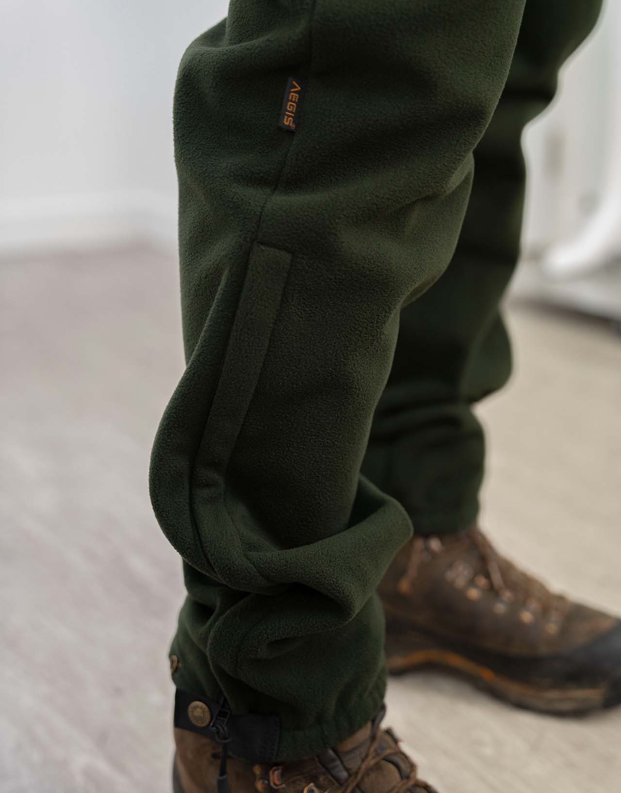 Swazi 4WD Pants showcased, highlighting their windproof fleece design, deep pockets, and zipper cuffs, worn by a person, paired with visible footwear.