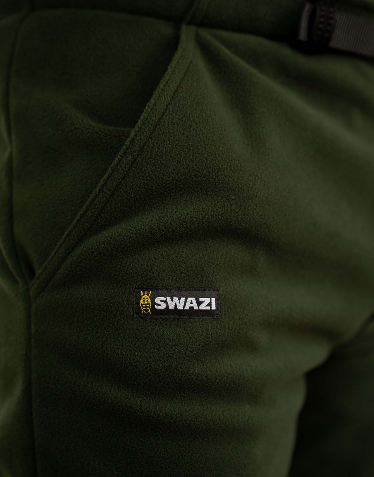 Close-up of Swazi 4WD Pants, emphasizing windproof fleece fabric and zipper cuffs, highlighting comfort and practicality for outdoor activities.