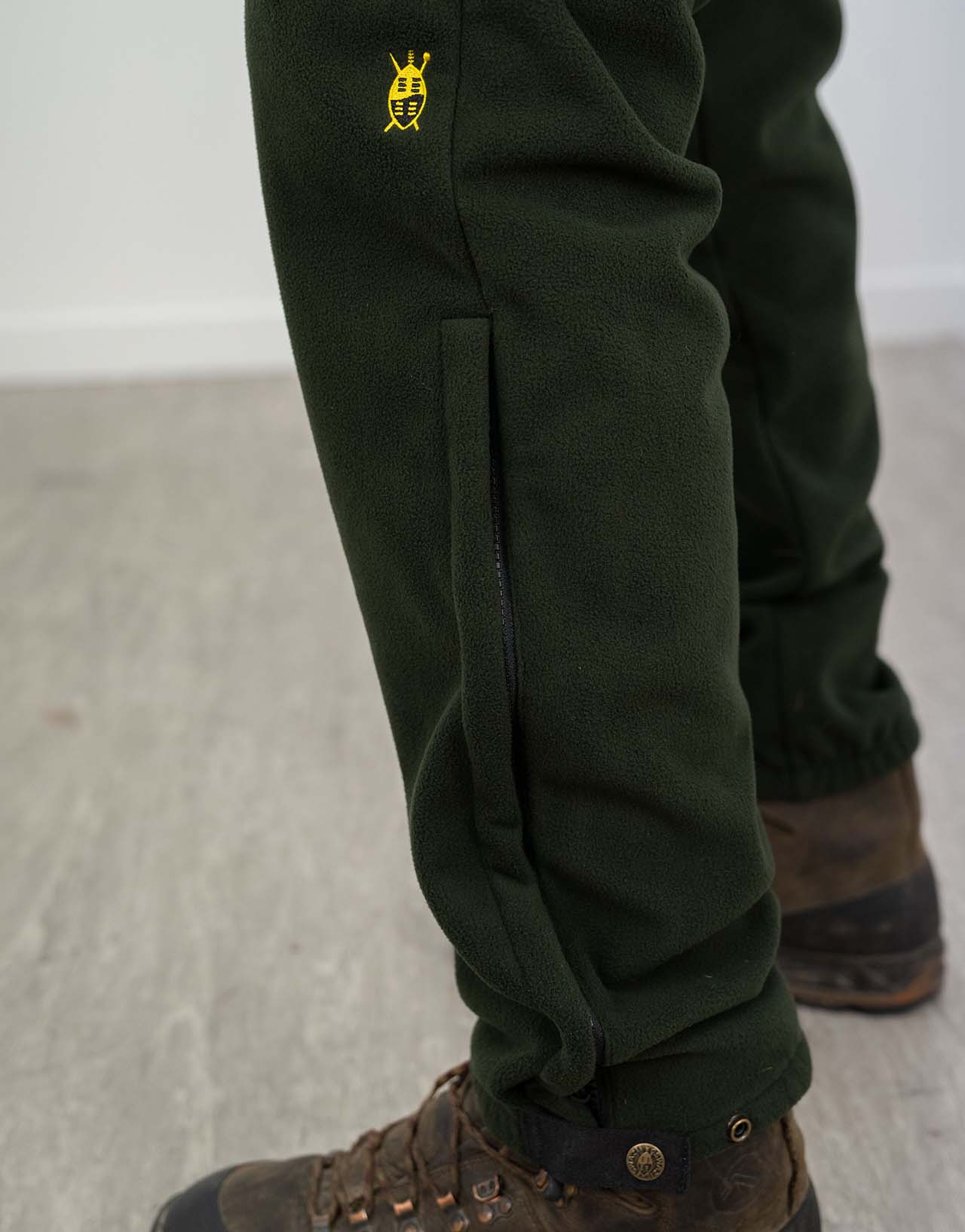 Person wearing Swazi 4WD Pants, windproof fleece trousers, featuring deep pockets and zipper cuffs over boots, designed for comfort and warmth during outdoor activities.