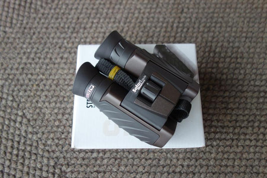 Steiner Safari Ultrasharp 10X26 Binoculars with a black strap, displayed on a white box, ideal for detailed viewing and outdoor adventures.