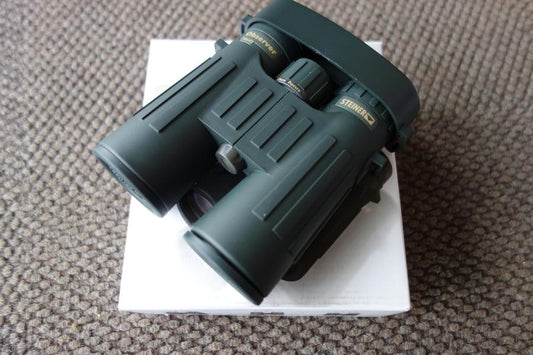 Steiner Observer 8X42 Binoculars resting on a white box, showcasing their ergonomic design and compact build for outdoor enthusiasts.