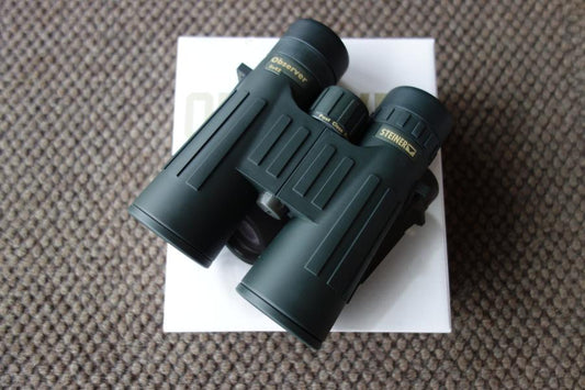 Steiner Observer 10X42 Binoculars placed on a box, showcasing its compact design and precision lenses for enhanced viewing.
