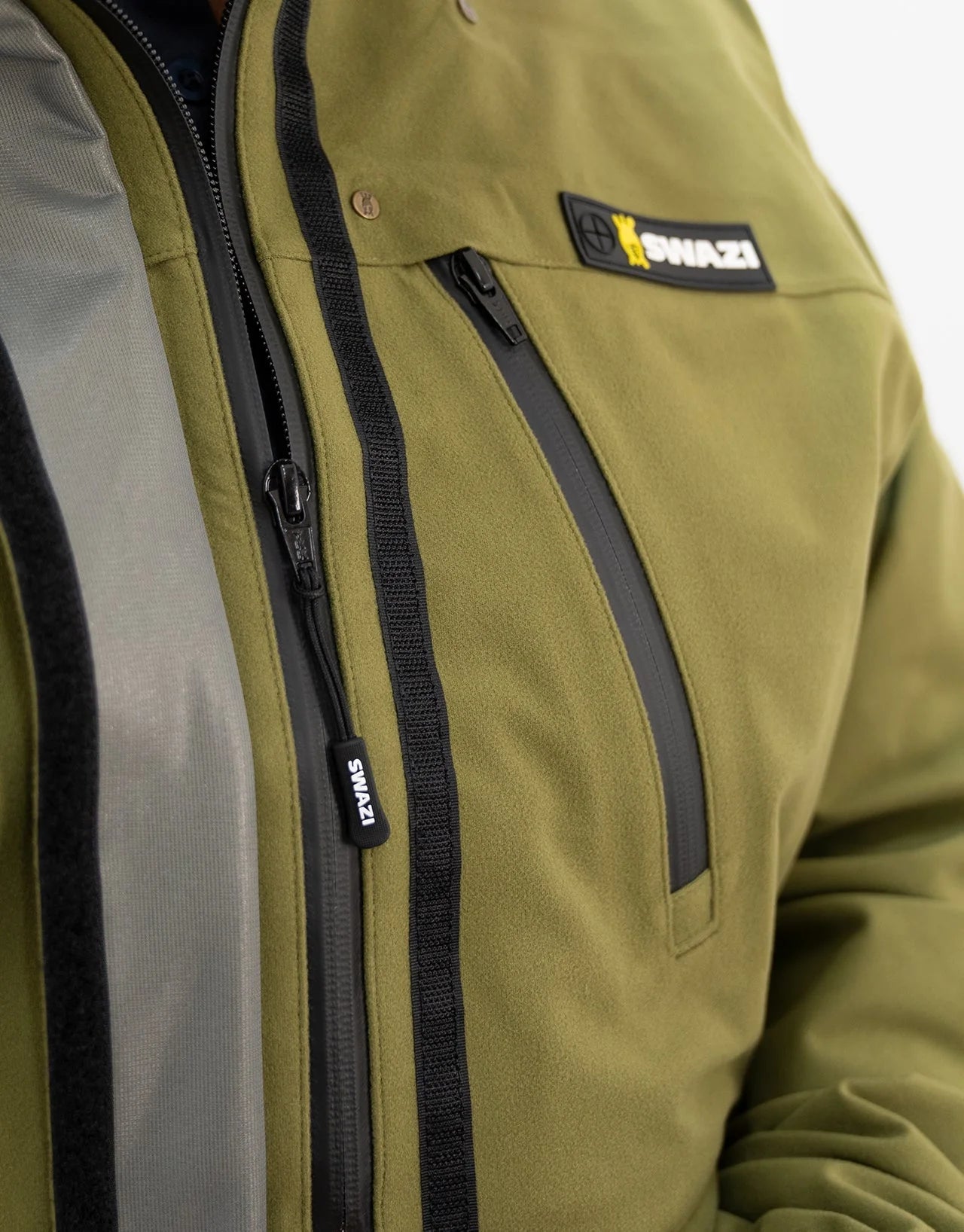 Swazi Kagoule Anorak featuring a close-up of a zipper and logo, highlighting its water-resistant YKK® zips and functional pocket design for hunting.