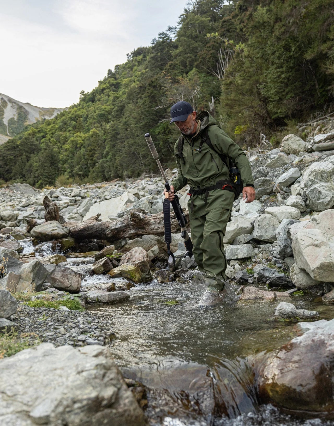Swazi Tahr Ultralite Jacket worn by a man in a stream, showcasing its lightweight design and waterproof features for hunting in rugged outdoor conditions.