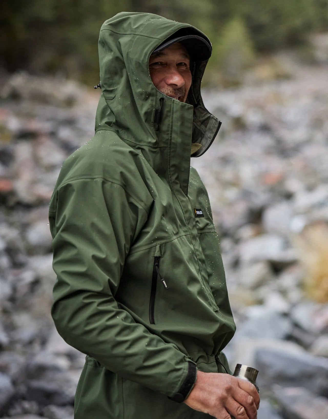 Swazi Tahr Ultralite Jacket showcased on a man outdoors, highlighting its hood and chest pockets, ideal for waterproof, breathable hunting or hiking.