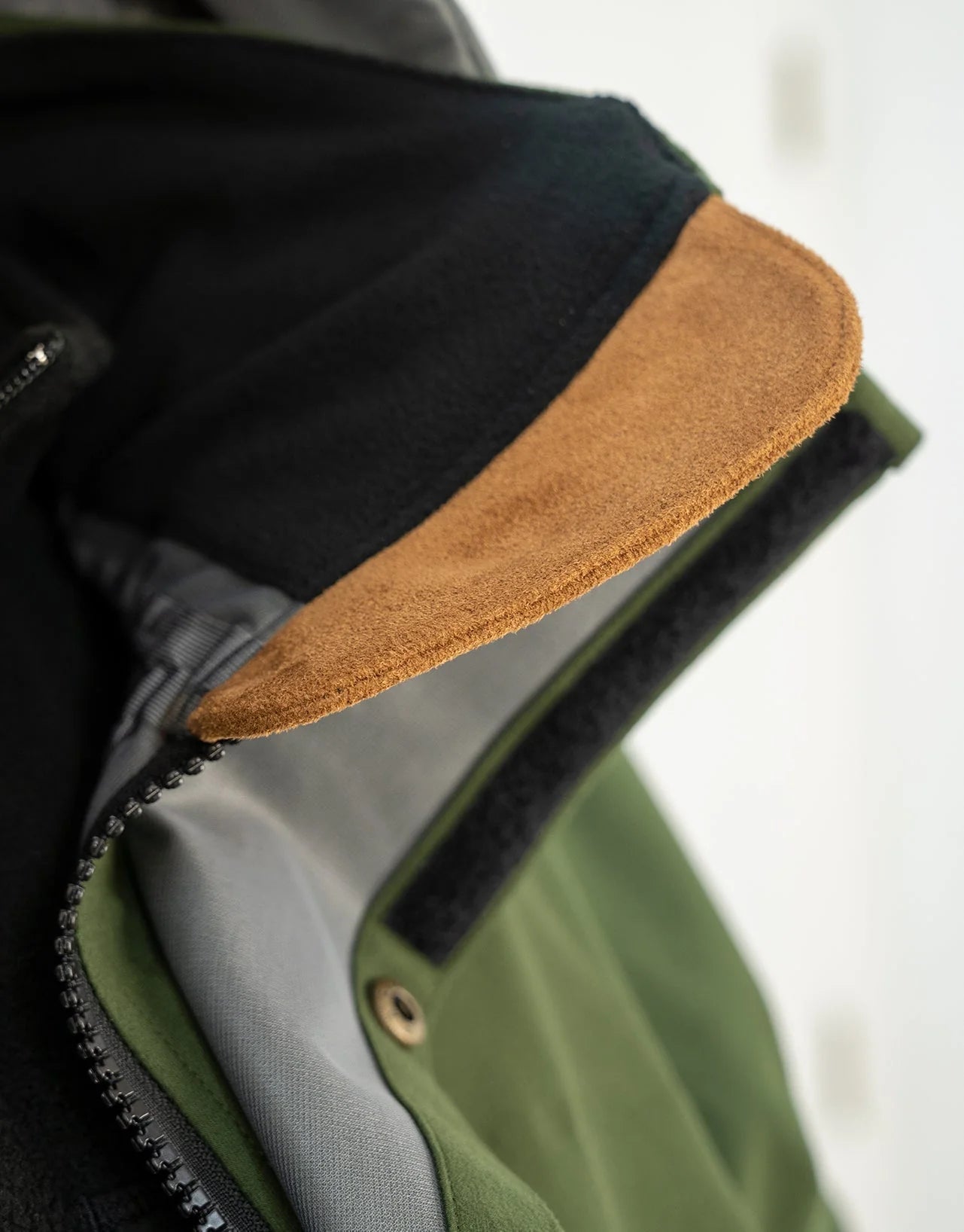 Close-up of Swazi Wapiti XP Men's Hunting Jacket featuring a leather texture, zipper, and zip-off hood, highlighting its waterproof and breathable design for outdoor use.