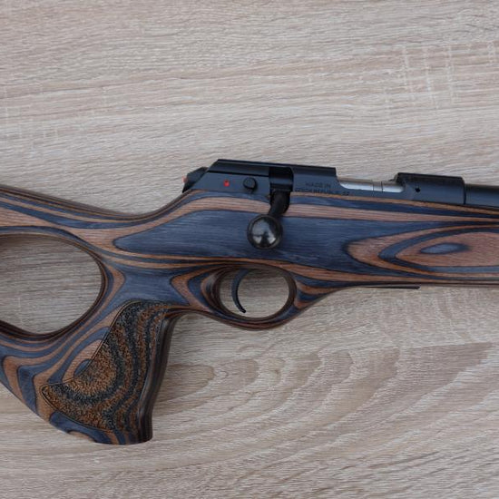 CZ Brno CZ 457 Thumbhole with a laminated thumbhole stock, visible 20 heavy barrel, and 5-round magazine, shown on a table.