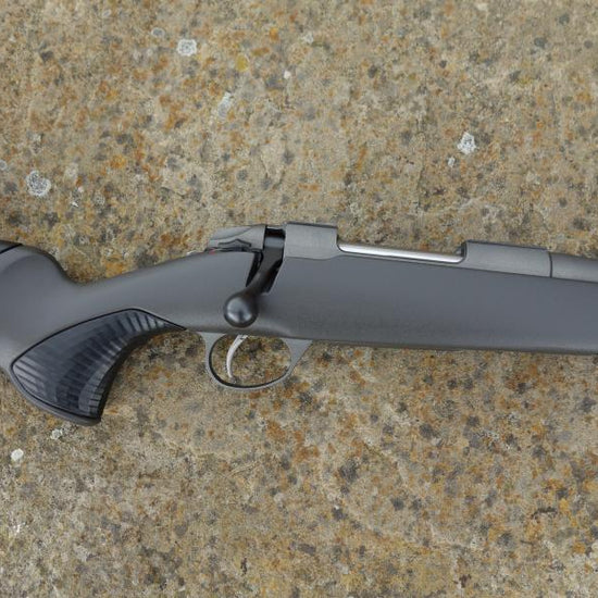 Sako 85 Finlight 2 rifle on ground, showcasing stainless steel action, fluted barrel, adjustable comb, and detachable magazine.