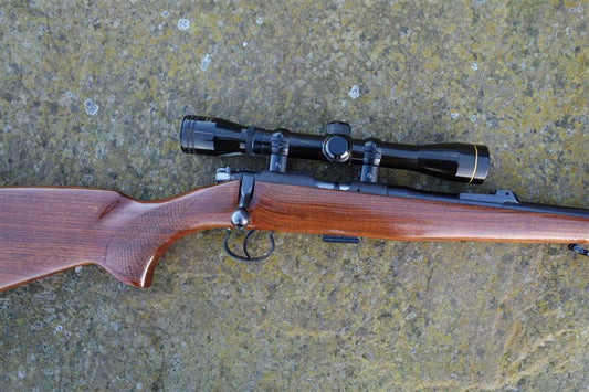 CZ Brno 452 Deluxe rifle with a scope, featuring a walnut stock, 5-round magazine, and sound moderator, emphasizing its superb condition and craftsmanship.