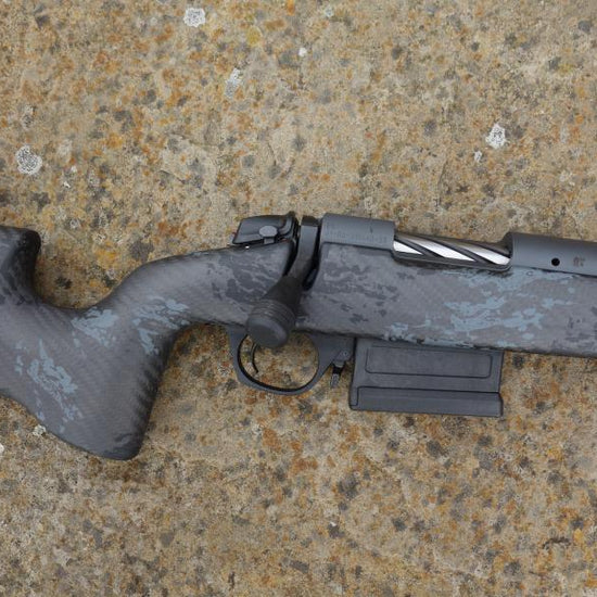 Bergara B14 Crest Carbon rifle, showcasing a carbon fiber stock, heavy profile barrel, and muzzle break, lying on a surface.