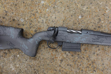 Bergara B14 Crest Carbon rifle, showcasing a carbon fiber stock, heavy profile barrel, and muzzle break, lying on a surface.
