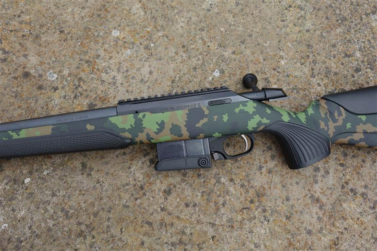 Tikka T3X CTR Camo rifle on concrete, featuring a scandi camo stock, heavy barrel, detachable magazine, and picatinny rail for versatile use.