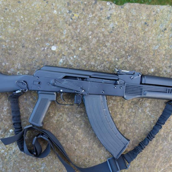 Izmash M3 EXP-01 rifle, featuring a straight pull design, strap, folding butt, and adjustable sights, placed on a stone surface.
