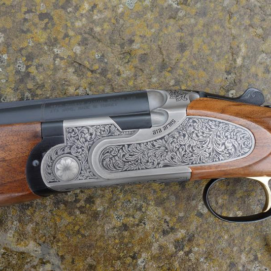 Close-up of the ATA Silverline 2 Sporting shotgun, showcasing bold scroll engraved sideplates, Turkish walnut stock, and mat finished barrels with flush fitting chokes.