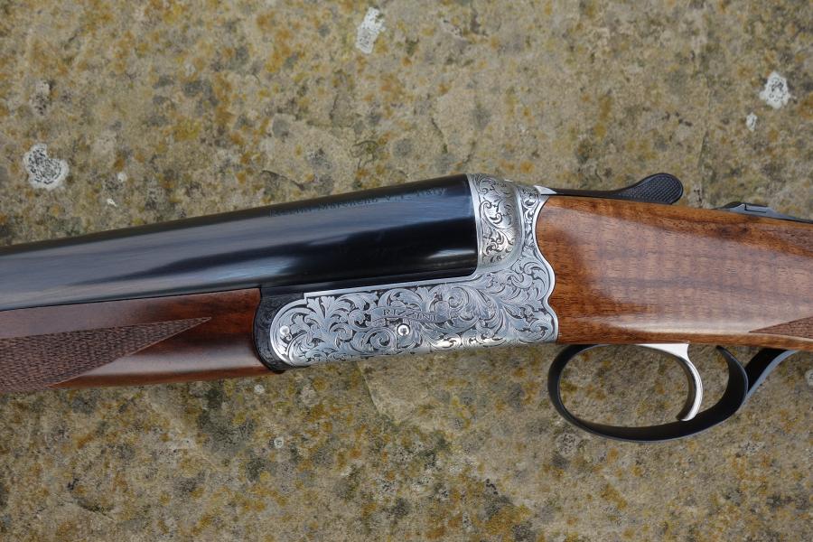 Rizzini BR550 Side by Side featuring elegant scroll engraving, walnut stock with pistol grip, visible trigger, and gun barrel details.