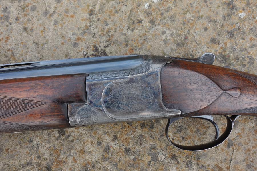 Close-up of the Browning B25 C1 Trap gun, showcasing its engraved receiver, rounded pistol grip, and narrow top rib, highlighting original features and craftsmanship.