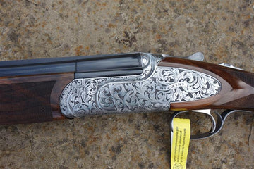 B Rizzini Regal Deluxe Game gun, featuring engraved floral scrollwork, a long trigger guard, and a walnut stock with a solid rib and flush-fitting chokes.