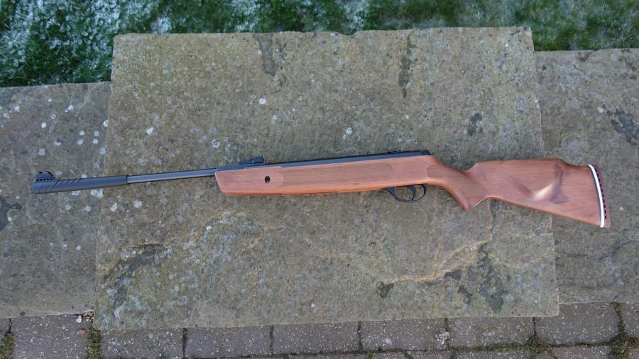 Hatsan Striker 1000X rifle on stone surface, featuring hi-viz open sights and auto safety, ideal for small vermin control.