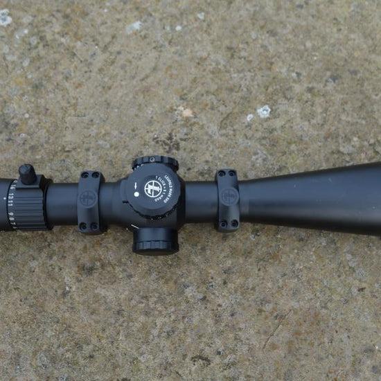 Leupold MK 5HD 5-25x56 Rifle Scope on concrete; features TMR reticule, zero stop turret, side parallax, includes aluminium lens cover, and picatinny rings.