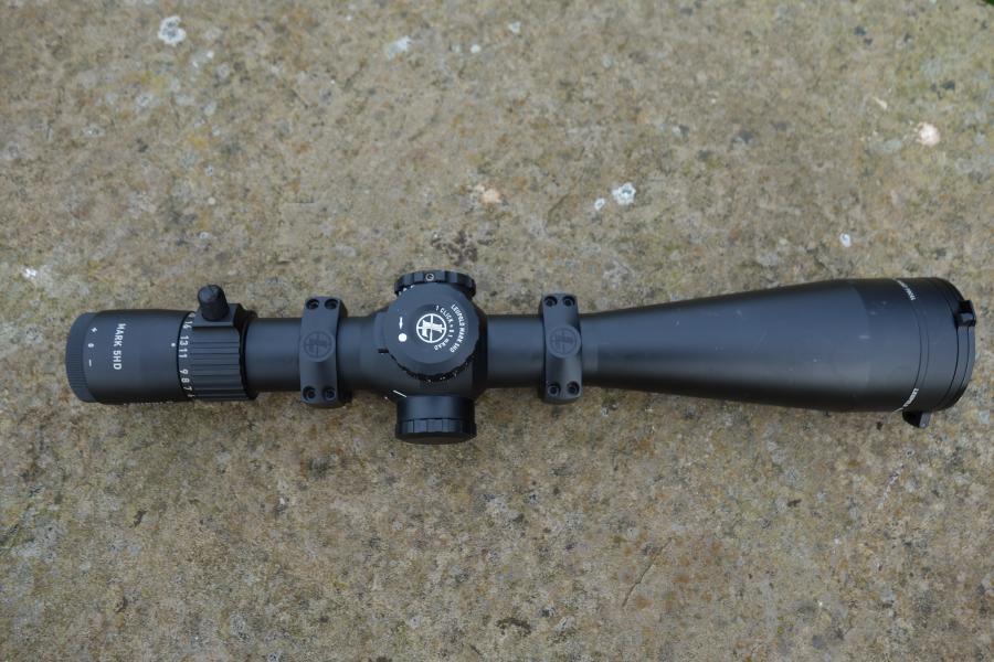 Leupold MK 5HD 5-25x56 Rifle Scope on concrete; features TMR reticule, zero stop turret, side parallax, includes aluminium lens cover, and picatinny rings.