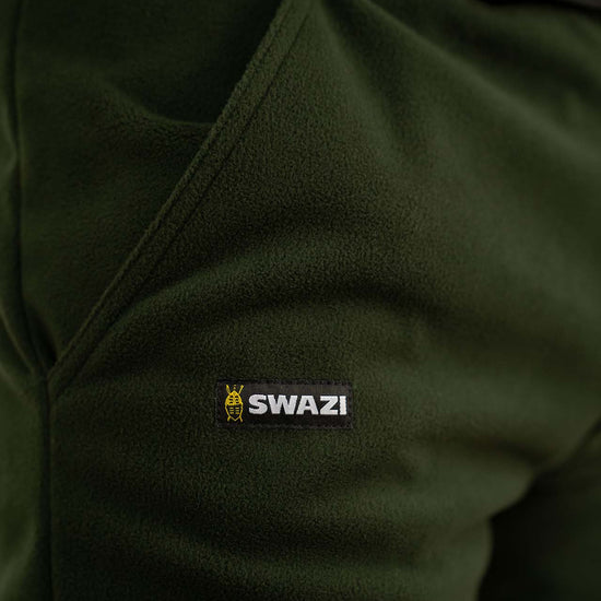 Close-up of Swazi 4WD Pants, emphasizing windproof fleece fabric and zipper cuffs, highlighting comfort and practicality for outdoor activities.