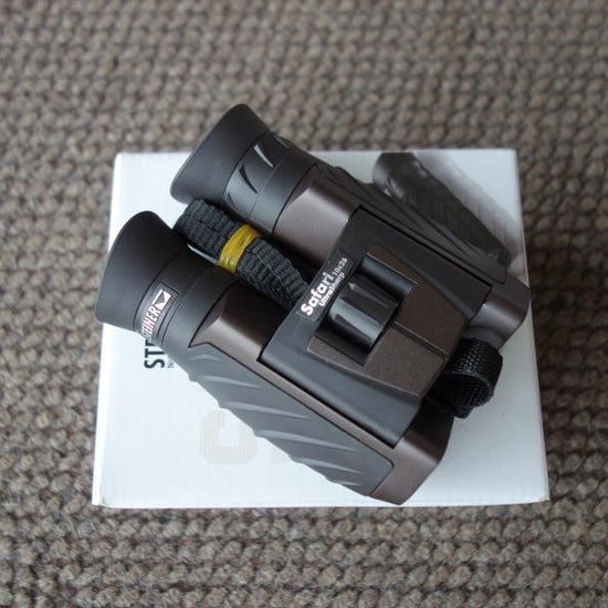 Steiner Safari Ultrasharp 10X26 Binoculars with a black strap, displayed on a white box, ideal for detailed viewing and outdoor adventures.