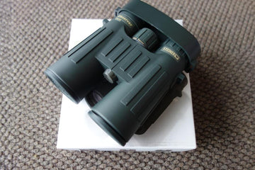 Steiner Observer 8X42 Binoculars resting on a white box, showcasing their ergonomic design and compact build for outdoor enthusiasts.