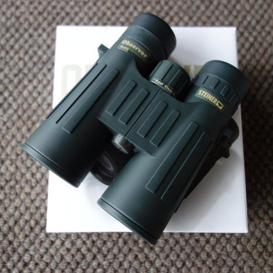 Steiner Observer 10X42 Binoculars placed on a box, showcasing its compact design and precision lenses for enhanced viewing.