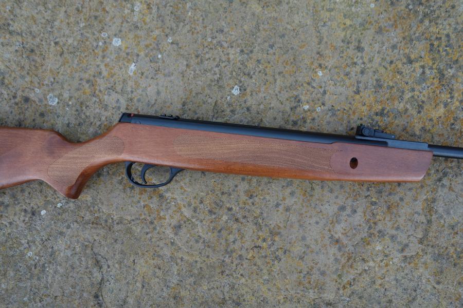 Hatsan Striker 1000S lies on the ground, showcasing its beech stock and Hi-viz open sights, ideal for mounting scopes and shooting sports.