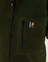 Close-up of the Swazi Bush Shirt, showcasing its long zipper and snug cuffs, emphasizing its comfort and practicality as a warm, olive fleece jumper.
