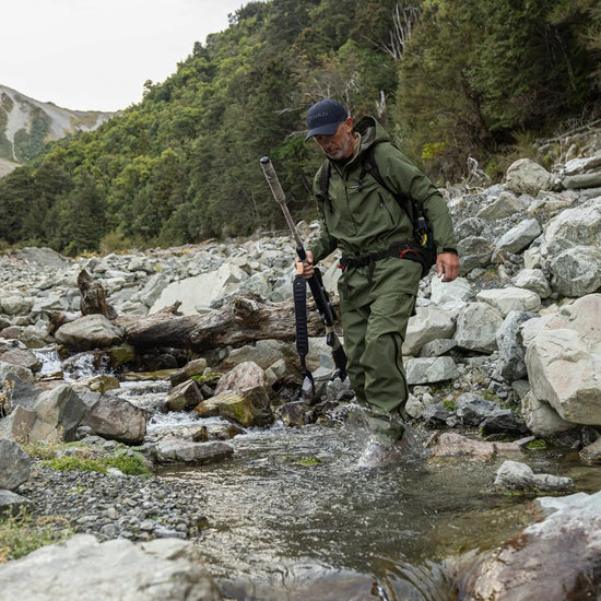 Swazi Tahr Ultralite Jacket worn by a man in a stream, showcasing its lightweight design and waterproof features for hunting in rugged outdoor conditions.
