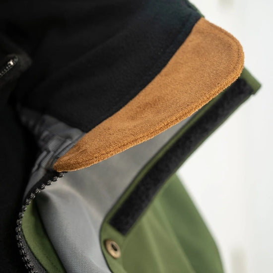 Close-up of Swazi Wapiti XP Men's Hunting Jacket featuring a leather texture, zipper, and zip-off hood, highlighting its waterproof and breathable design for outdoor use.